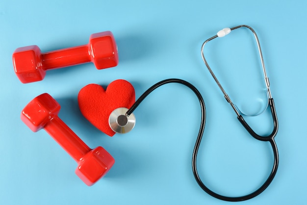 Red heart, stethoscope and red dumbbells. World health day, healthcare and medical concept, health insurance concept.