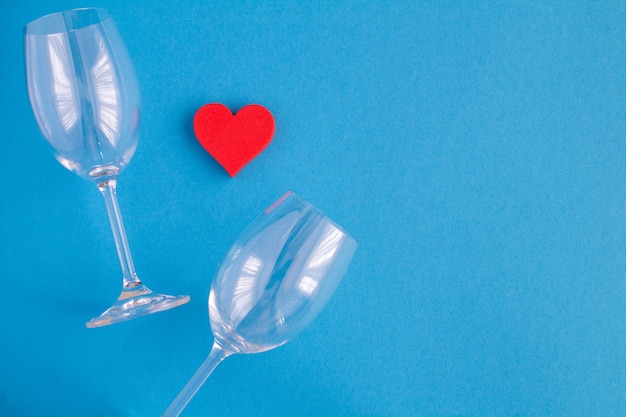 Cuore rosso e due bicchieri di vino vuoti sull'azzurro