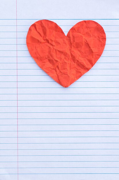 Red heart on white lined sheet of notepad
