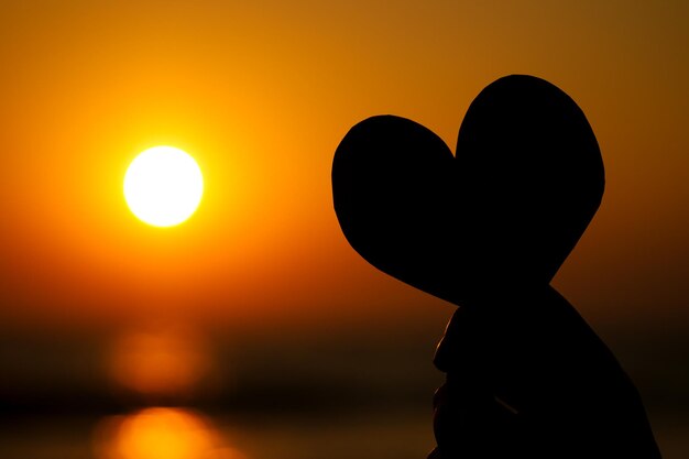 海に沈む夕日の女性の手に白い砂浜のコピースペースに赤いハート幸せなバレンタインデーと母の日のコピースペース