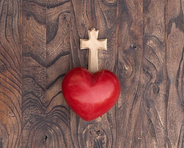 Foto cuore rosso con una croce su uno sfondo di legno