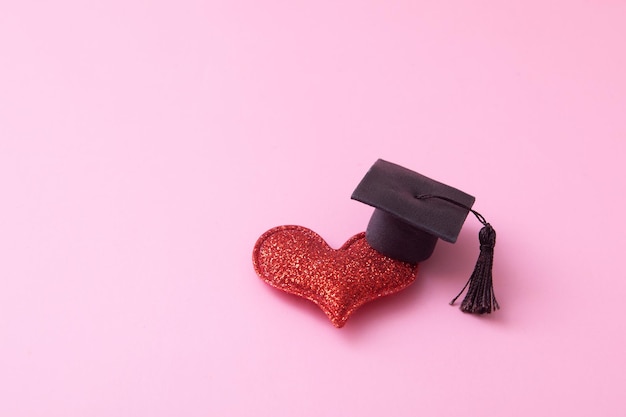 Red heart with a graduate capon pink background. relationship\
learning, love, psychology concept