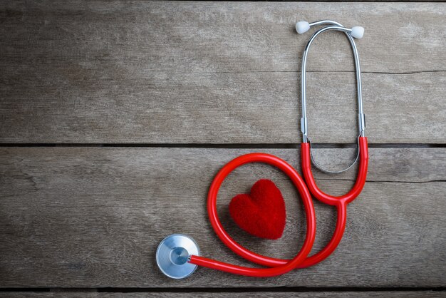 Red heart with a stethoscope on wooden table background