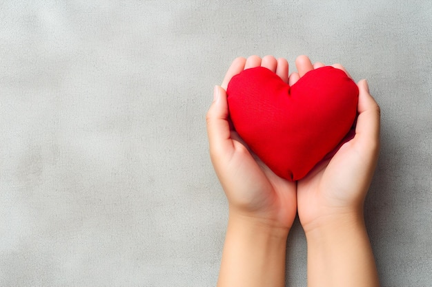 Red heart in woman hands on gray background Copy space for text