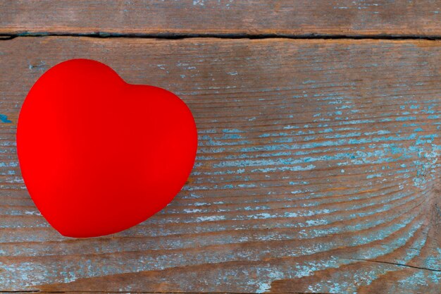 A red heart on the wooden background.