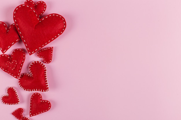 Red hearts are handmade on pink background. Preparation for Valentine's Day with a place for text. Copy space.