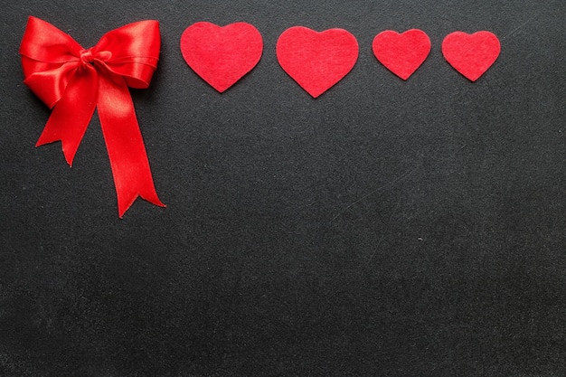 Red hearts and bow on black board