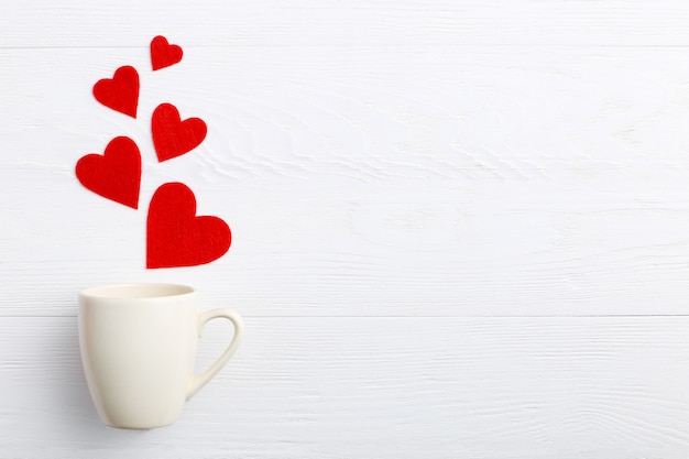 Red hearts coming out of the cup on white background