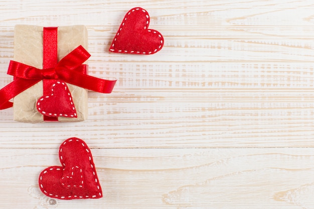 Red hearts and craft gifts on white wooden background