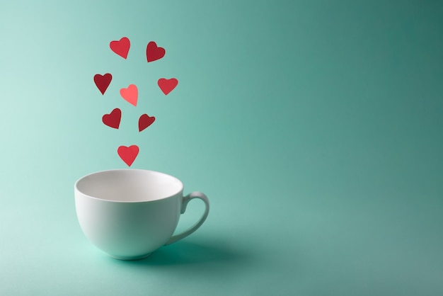 Red hearts flying out of a white cup