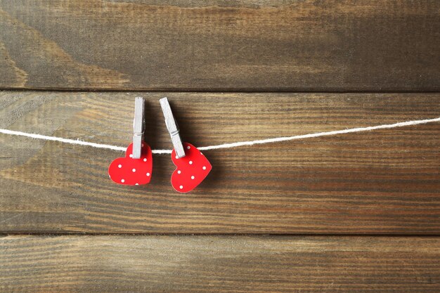 Red hearts hanging on clothespins on wooden background