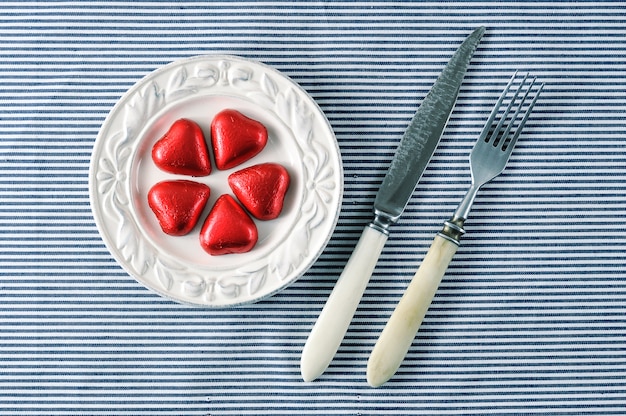 Photo red hearts on a plate and a knife with a fork