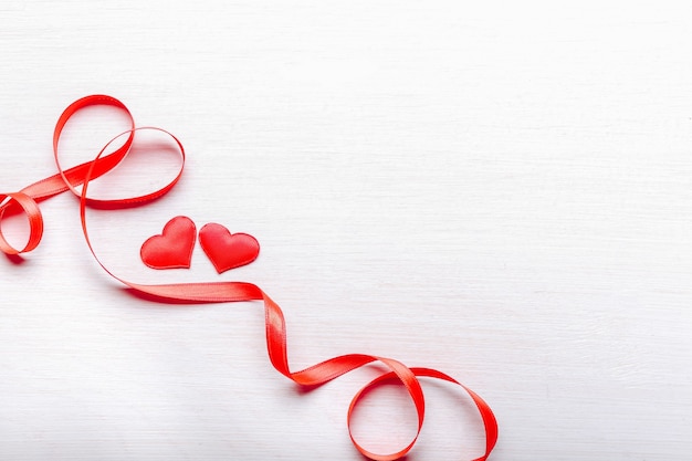 Red hearts and ribbon on light wooden