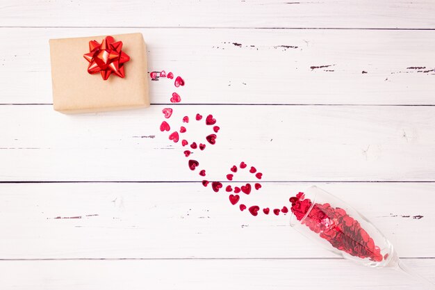 Red hearts spill out of a champagne glass and gift box