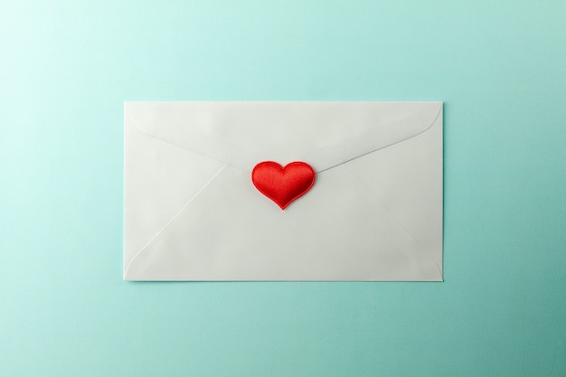 Red hearts stamped at white envelope on blue paper background