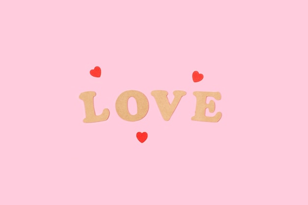 Red hearts with love word in wooden letters on a pink background