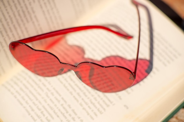 本の上の赤いハート形のメガネ