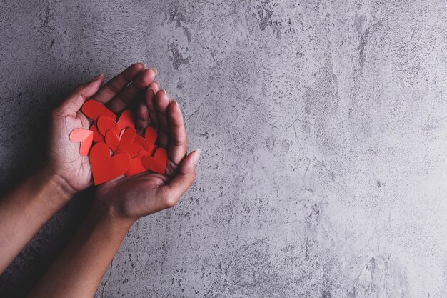 Red heartshaped paper cut in human palm isolated on texture background