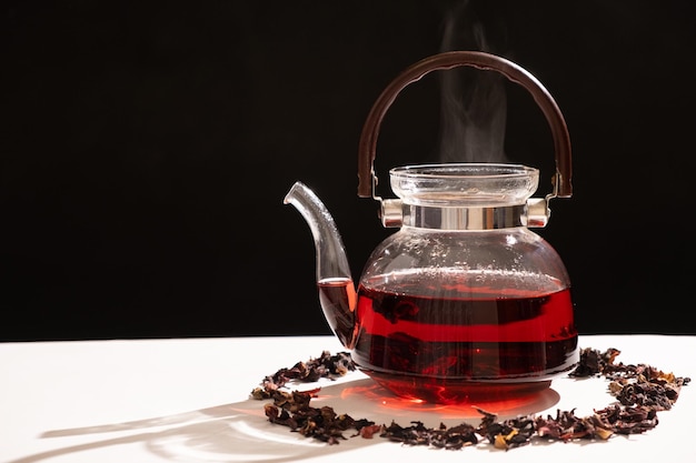 Red hibiscus tea from the petals of a Sudanese rose in a glass teapot copy the place for the text