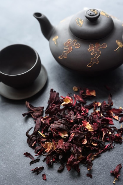 Red hibiscus tea with a set of clay dishes on a dark background