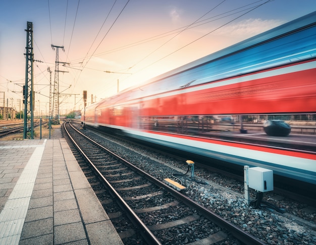 Red high speed train in motion on the railway station