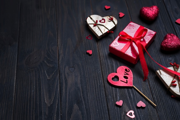 REd Holidays gift and heart on wooden background