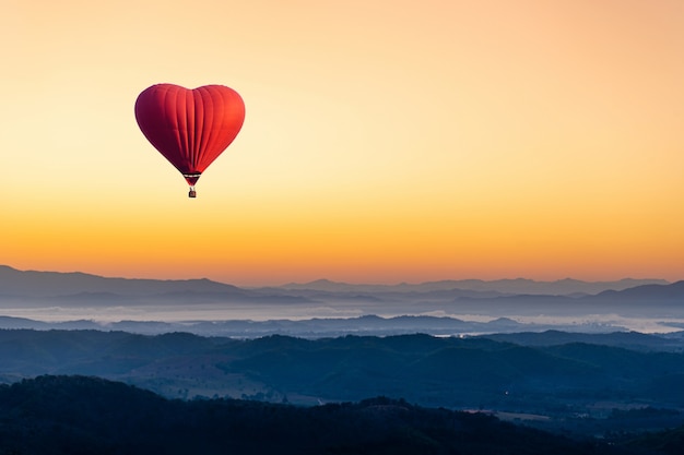 Фото Красный воздушный шар в форме сердца, летящего над горой