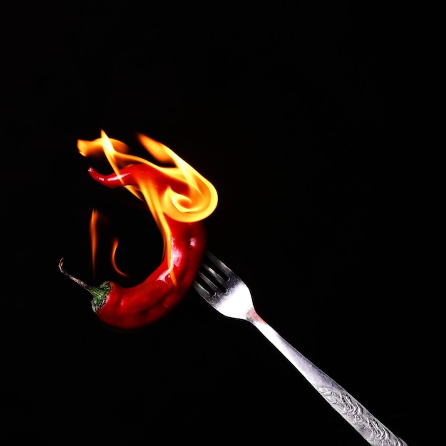 Peperoncino rosso rovente in fiamme su una forchetta