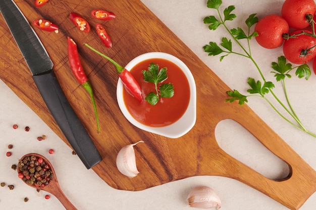 Red hot chilli sauce. tomato ketchup, chilli sauce, puree with chili pepper, tomatoes and garlic. on wooden cutting board on stone surface. top view.