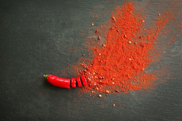 Red hot pepper bursting with chili powder on dark background top with