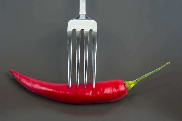 red hot pepper on a fork on a ceramic plate. spices and vegetative food