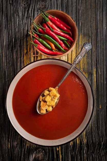 Photo red hot pepper and a plate of cool soup gazpacho