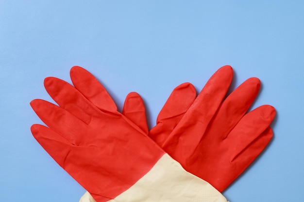 Red household gloves on a blue background crosswise from below.