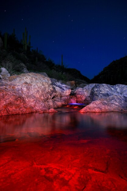 Foto lago illuminato di rosso da rocce contro il cielo di notte