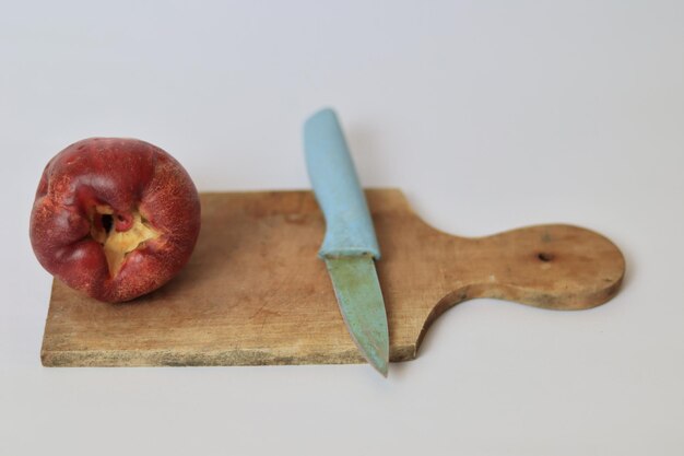 red jambu bol or jamaica guava next to a blue knife on a cutting board against a white background
