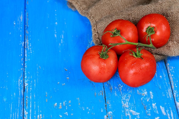 Red juicy tomatoes on old blue wooden board horizontal