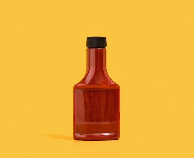 Red ketchup dispenser on a yellow background Tasty dinner in modern restaurant