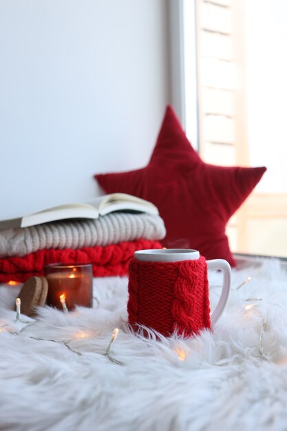 Red knitted cup with a drink on a Christmas background. New Year's home comfort