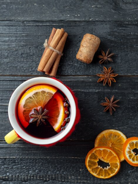 Tazza lavorata a maglia rossa di vin brulé su una tavola di legno scura