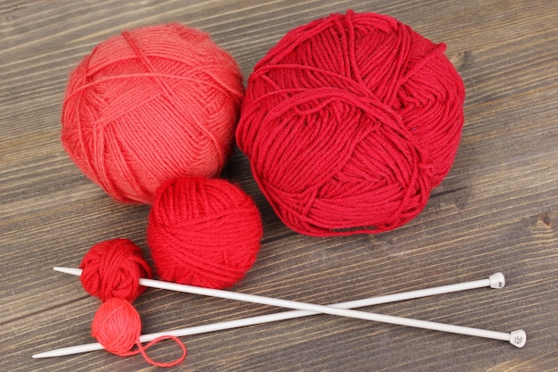 Red knittings yarns on wooden table closeup