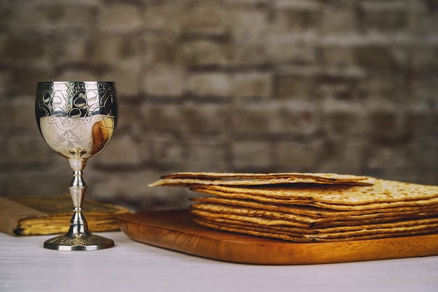 Red kosher wine with a white plate of matzah or matza and a Passover Haggadah 