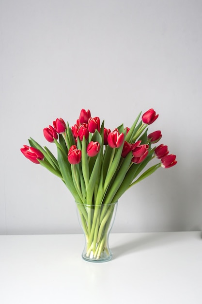 Red kung fu tulips stand in a glass vase on the table Bouquet of flowers