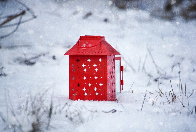 写真 新雪の上で燃えるろうそくと赤い提灯。公園で雪の降る冬の朝。