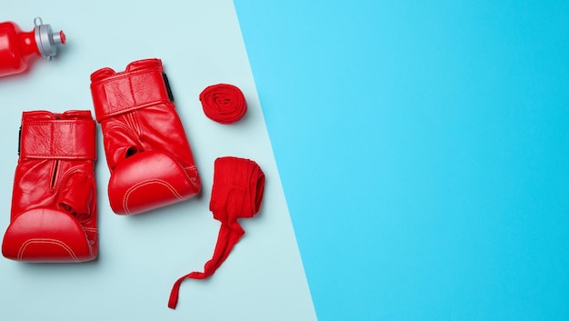 Красные кожаные боксерские перчатки, текстильная повязка на руку и бутылка с водой, спортивный инвентарь