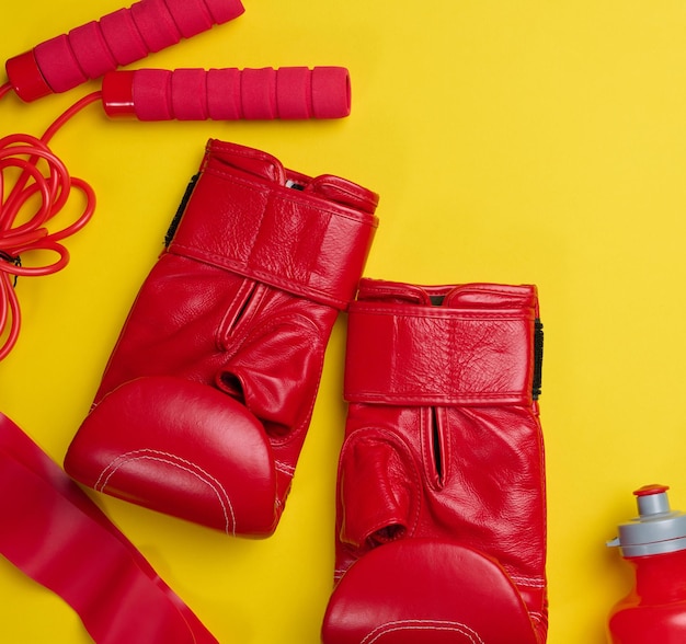 Фото Красные кожаные боксерские перчатки, бутылки с водой, спортивные принадлежности на желтом фоне