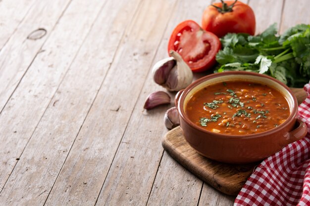 Red lentil soup in bowl on rustic wooden table