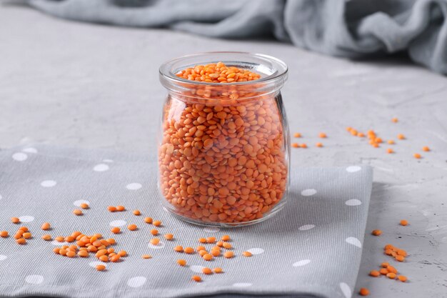 Red lentils in glass jar on gray