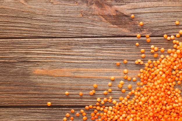 Red lentils scattered on a wooden background