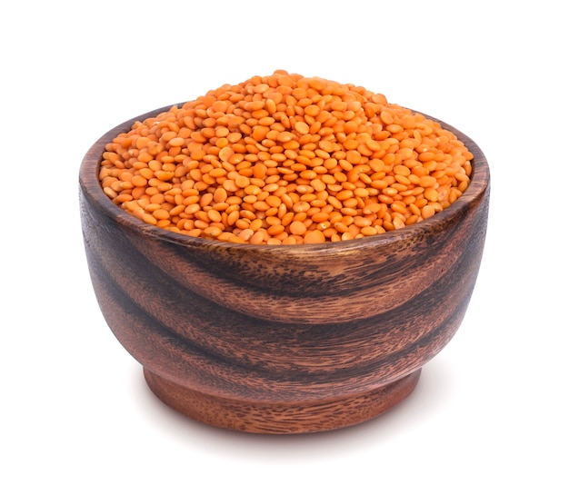 Red lentils in wooden bowl isolated on white background