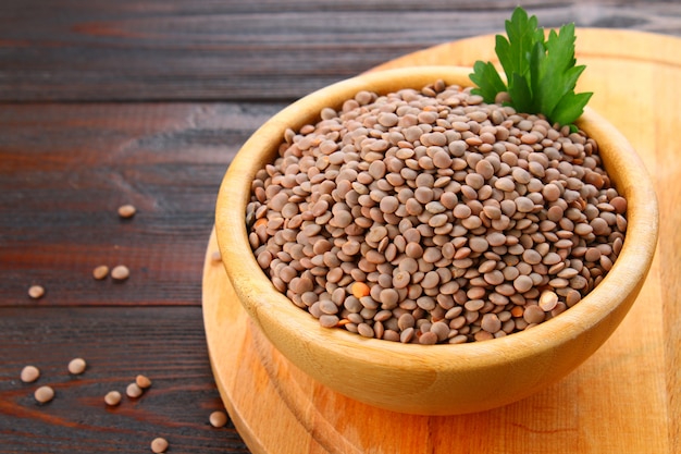 Red lentils in a wooden bowl on a wooden table